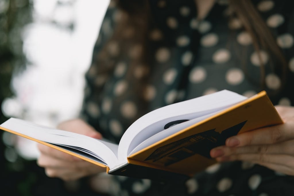 A woman reading a book indoors with a serene and focused atmosphere, captured with soft focus.